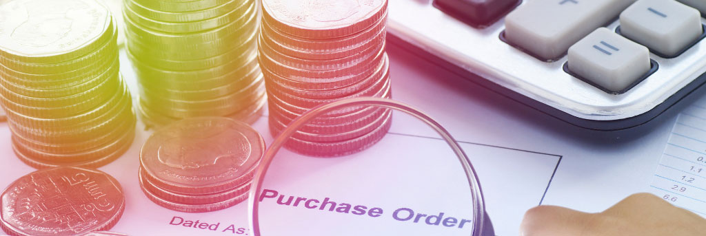 A purchase order on a desk with coins, calculator, and magnifying glass