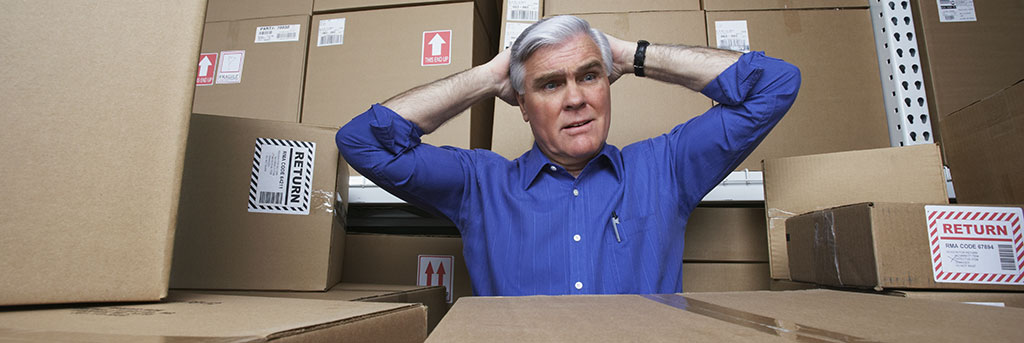 Person in warehouse surrounded by boxes wondering what in an inventory information system can help with business operations