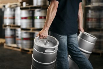 Person carrying kegs in a warehouse filled with kegs to represent Acctivate customer, G4 Kegs, a distributor of high-quality stainless steel kegs, growlers, and accessories for craft beverage brewers.