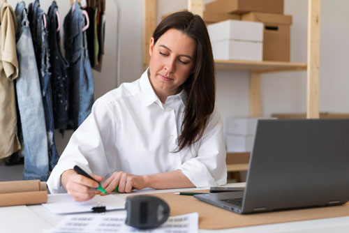 Online retailer at a desk looking at business reports achieved by adding more functionality for a business beyond QuickBooks for financials.