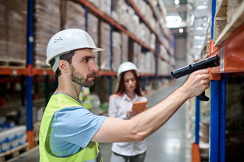 Person scanning barcode label on warehouse shelf after learning how to organize parts inventory with labeling