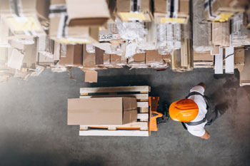 Warehouse worker walking through warehouse after business sought how to organize parts inventory with a more efficient warehouse layout