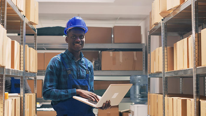 Warehouse employee with laptop in warehouse utilizing inventory and warehouse management best practices