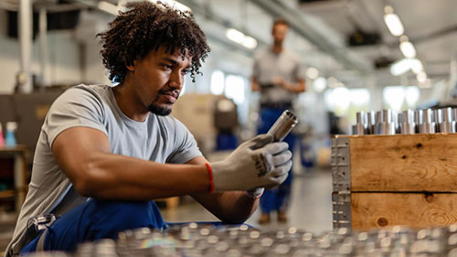 Person in warehouse inspecting parts inventory that will be managed in a centralized parts management system