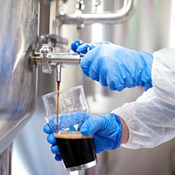 Beverage ERP software maintains quality control at brewery Scientist hands pouring a glass of beer to maintain quality control with beverage ERP software
