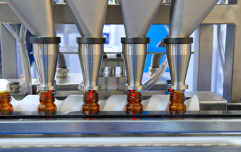Machine filling bottles with pills is managed by pharmaceutical manufacturing inventory software