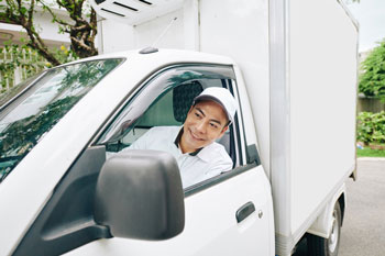 Person in a delivery vehicle for bakery business that uses a bakery distribution system to manage distribution and tracking.
