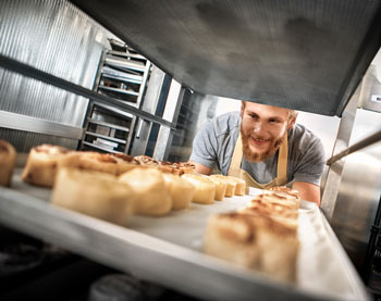 Happy baker producing baked goods and managing everything with a bakery distribution system that works with QuickBooks