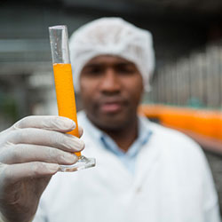 Beverage inventory control software by Acctivate for QuickBooks Worker in juice factory showing a test tube of juice produced with beverage manufacturing software from Acctivate