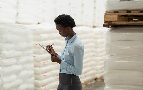 Person in food warehouse writing on clipboard with need better inventory management practices gained with inventory software implementation