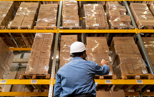 Manage different types of purchase orders with Acctivate Inventory Software Person in warehouse looking up at boxes on shelves and counting inventory to reorder with a purchase order
