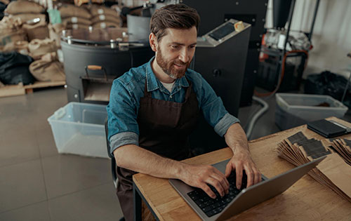 Person on laptop in coffee manufacturing warehouse