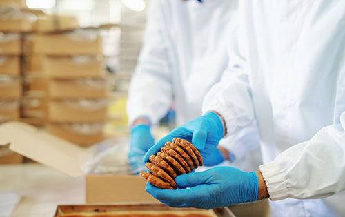 Demand planning and forecasting tools help food manufacturers during fluctuations in demand for holidays and summer People packing cookies in factory during a time of seasonality