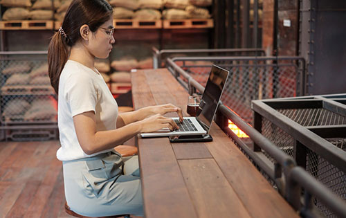 Person on computer in food manufacturing warehouse using software to reduce inventory costs