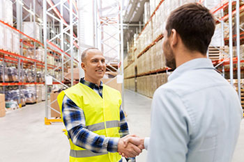 Warehouse worker shaking the hand of a vendor in a warehouse