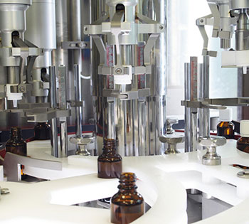 Bottles of product being filled in factory through manufacturing